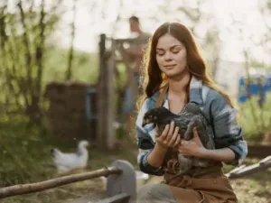 Jovem acariciando um filhote ao ar livre, numa propriedade rural